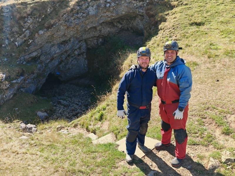 A caver in an oversuit and helmet underground