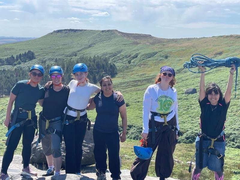A smiling group in helmets and harnesses after a climbing course in the Peak District