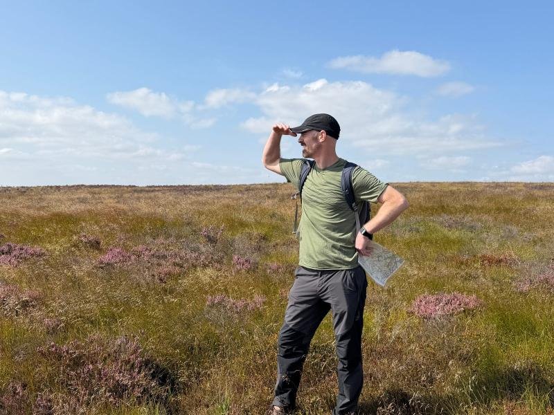 A walker with a map on Peak District moorland